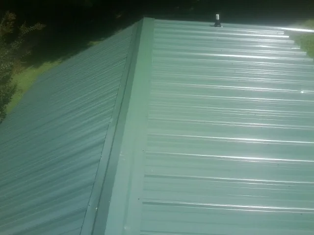 New green metal panels meeting at the ridge of a roof — Flat Roof Repair work by our crew in Cloverdale