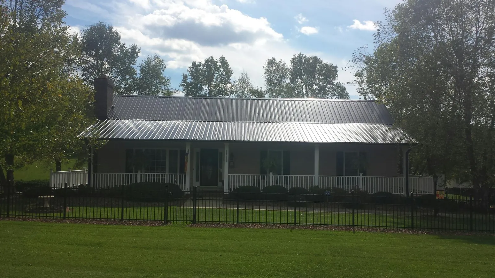 Gray metal roof on a brick ranch with a full width front porch — Gutter Guard Installation work by our crew in Cloverdale